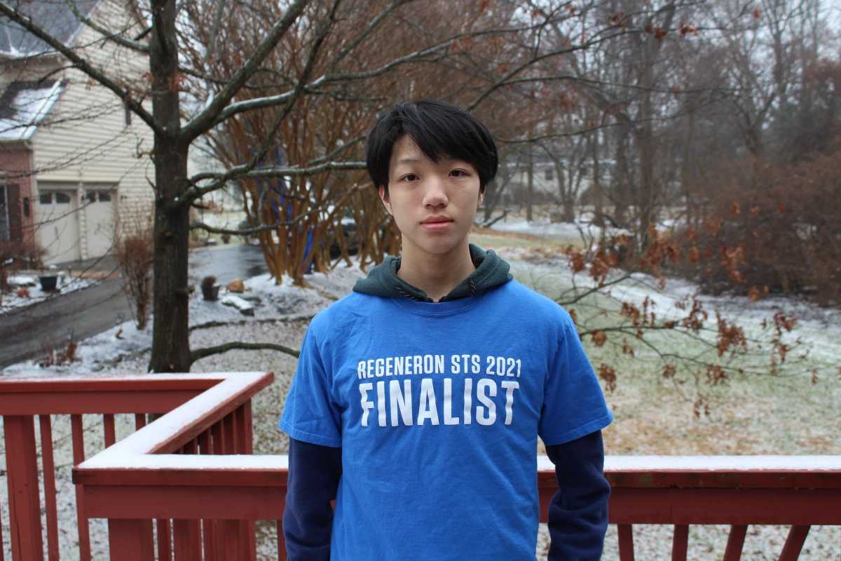 Timothy Qian wearing a blue Regrneron STS 2021 Finalist shirt while on a porch standing in front of a snowy yard.