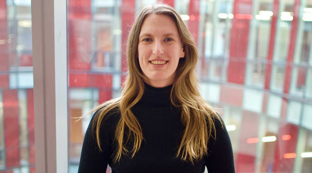 Elizabeth Bennewitz in a black top stands in front of red and clear windows.